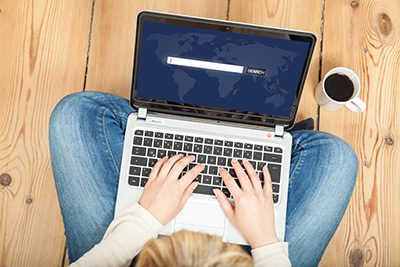Person sitting on the floor with laptop in lap typing into serach bar indicating how important Ocean County SEO services are