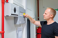 NJ fire alarm installation technician inspecting control panel