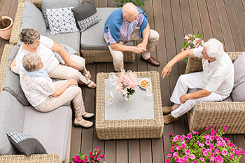 Group of elderly friends sitting on wicker outdoor furniture on a custom deck designed by Barnegat Light deck contractors Heslin Builders